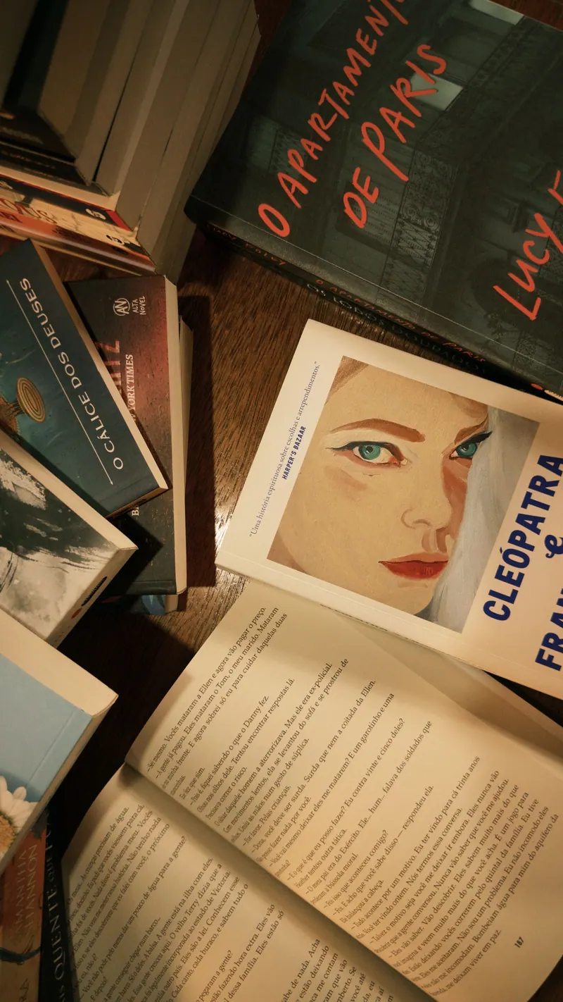 Livros espalhados sobre a mesa, entre eles romances e fantasias